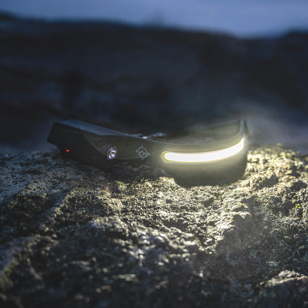 Wide-angle headlamp/ head torch looking rugged sitting on a rock